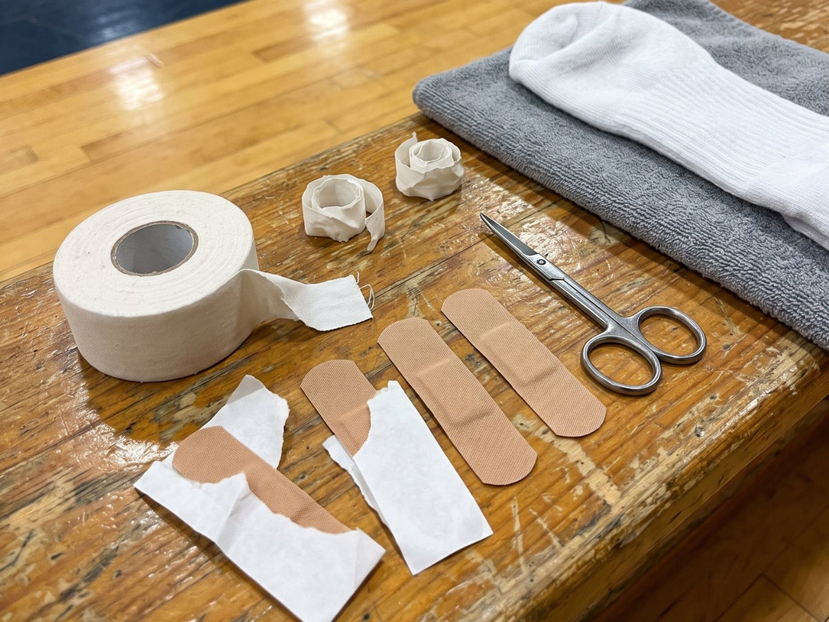 Athletic tape, Band-Aids and scissors on a gym bench next to a pair of socks