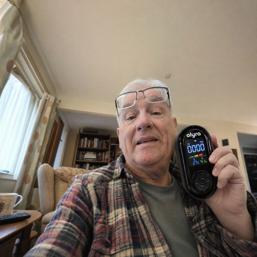 An older man holding the TrueDetect detector in his living room.